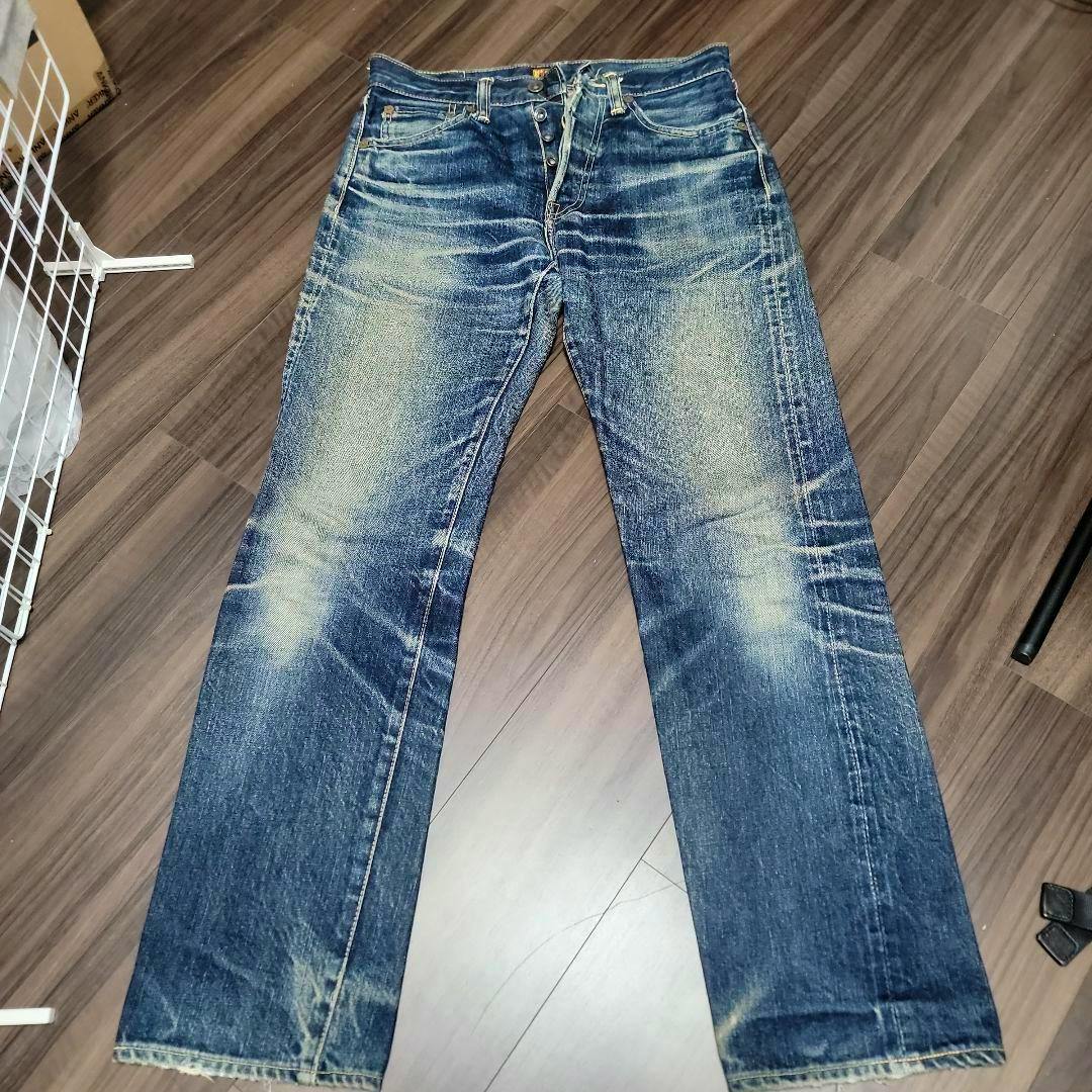 Front view of The Real McCoy's S614 men's denim jeans (W29) laid flat on a wood floor showing button fly and faded whiskering.