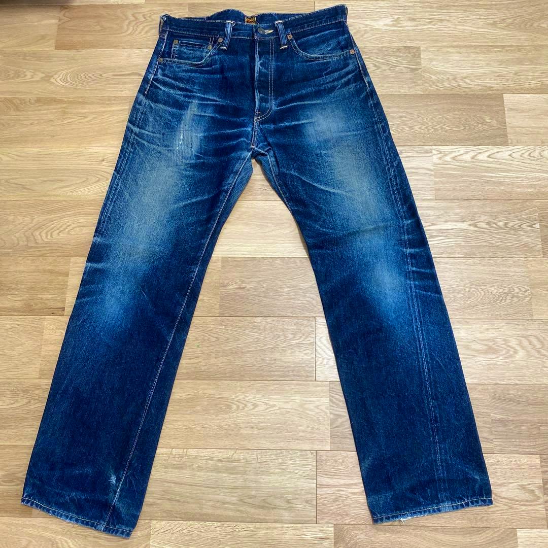 Front flat-lay photo of The REAL McCOY'S men's blue denim jeans (33×34) on a wooden floor showing fading and whiskering.