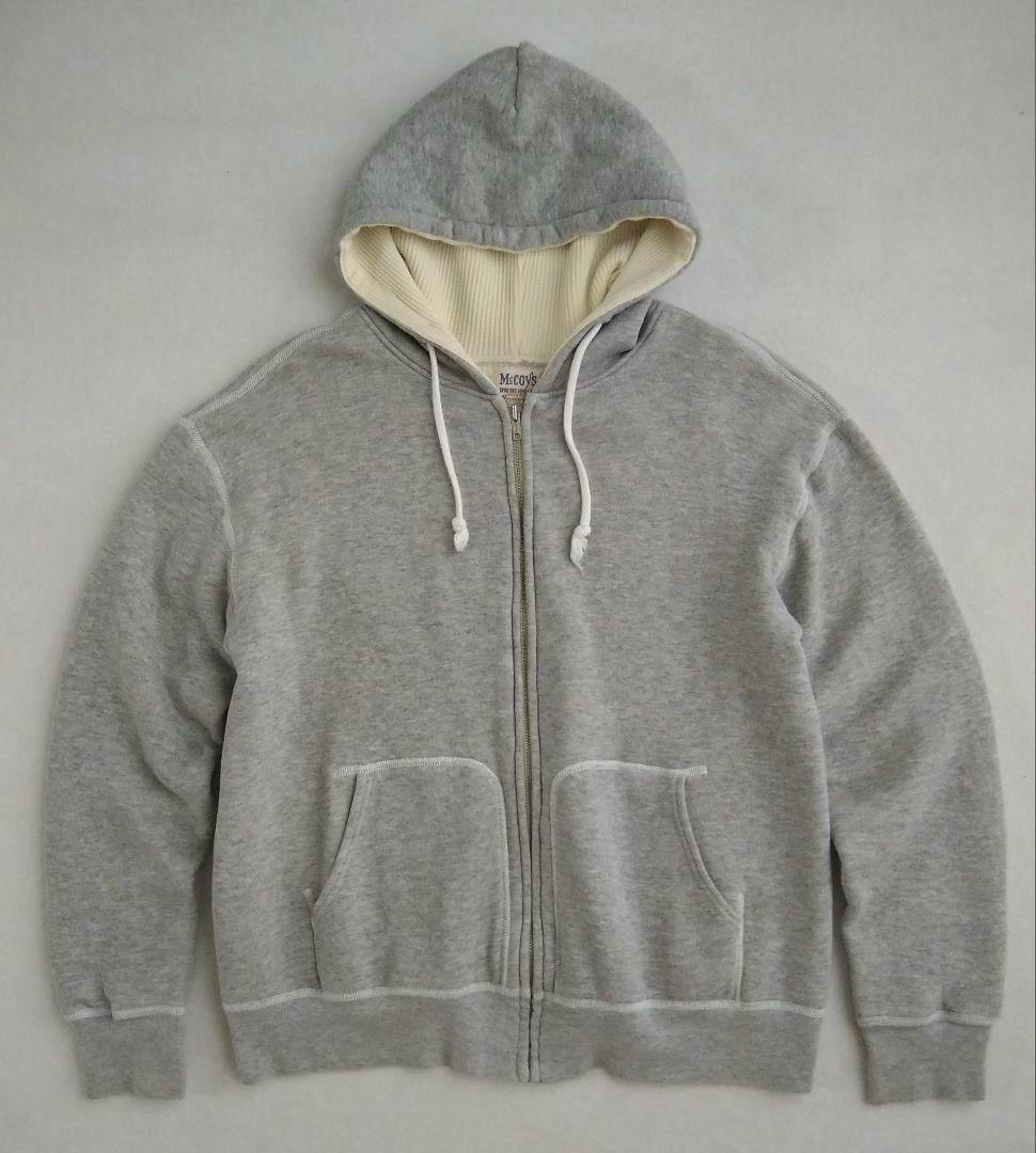 Front view of a gray thermal zip-up hoodie sweatshirt with drawstrings, a zipper, and front pockets.