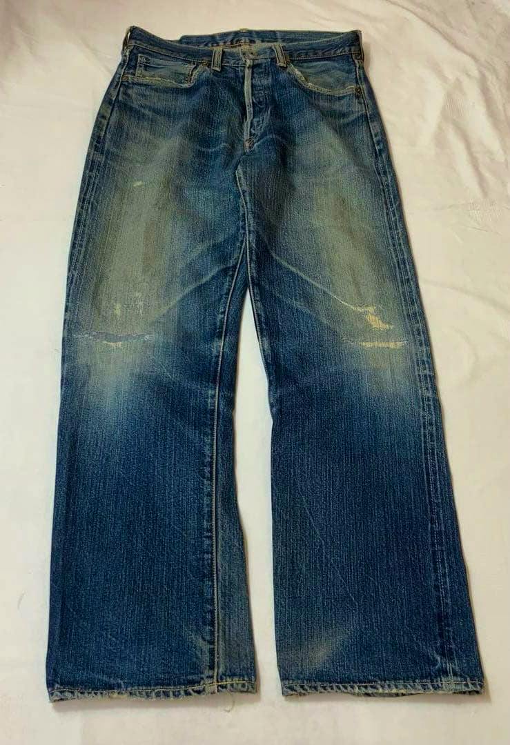 Front view of the men's denim jeans laid flat on a surface, showing faded areas and straight legs.