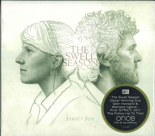 Front cover of the CD 'The Swell Season – Strict Joy' showing illustrated side-profile portraits and a round promotional sticker.