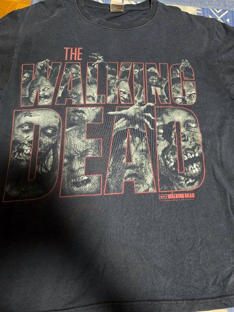 Black men's cotton T-shirt laid flat showing a large front THE WALKING DEAD print with zombie faces.