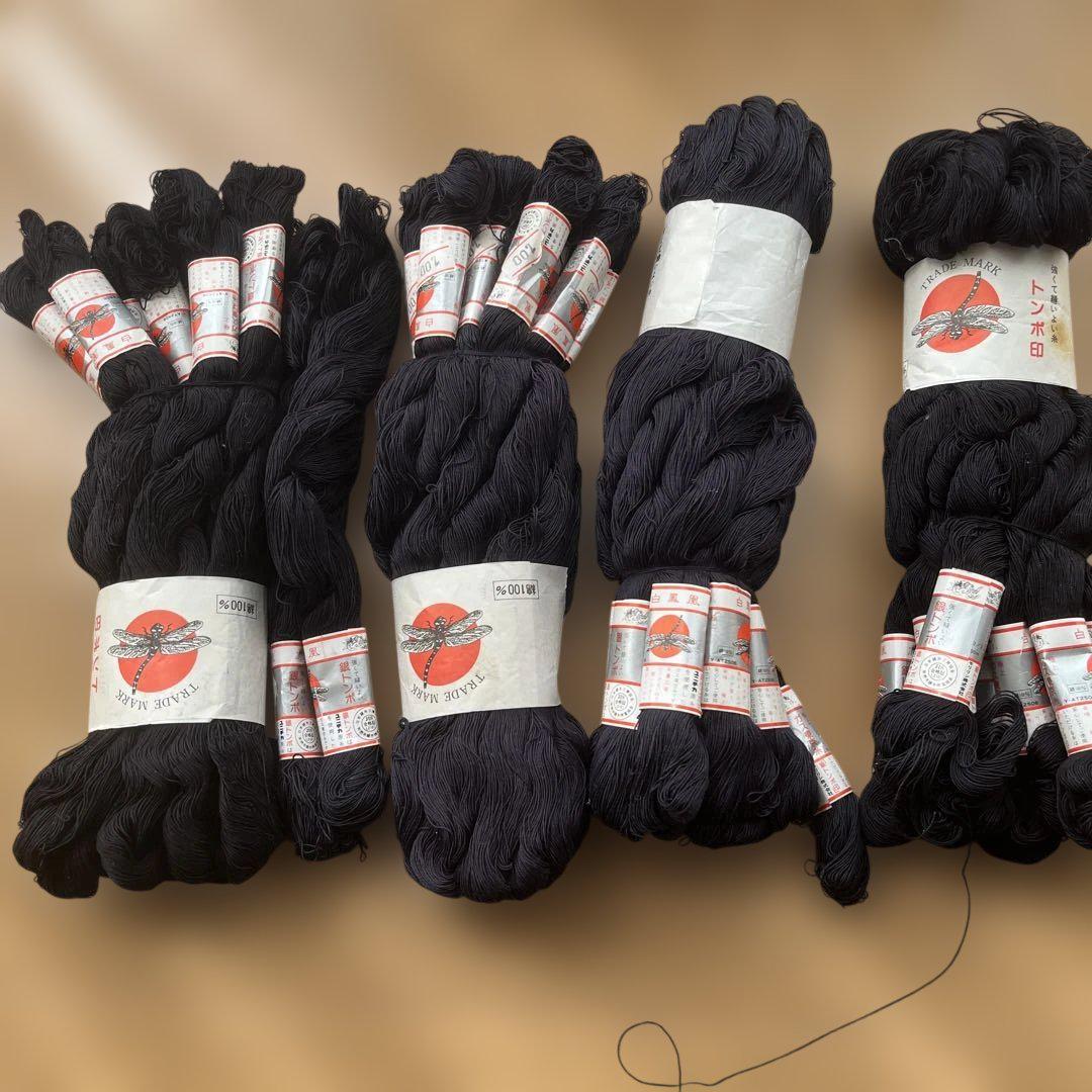Several skeins of dark cotton thread (太木綿糸) with paper labels laid out on a flat surface.