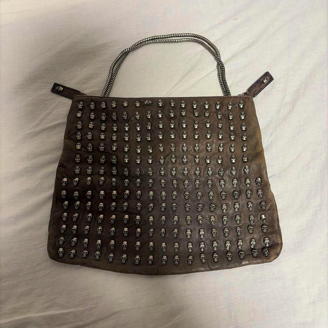 THOMAS WYLDE shoulder bag front with multiple silver skull studs and a braided strap on a light background.
