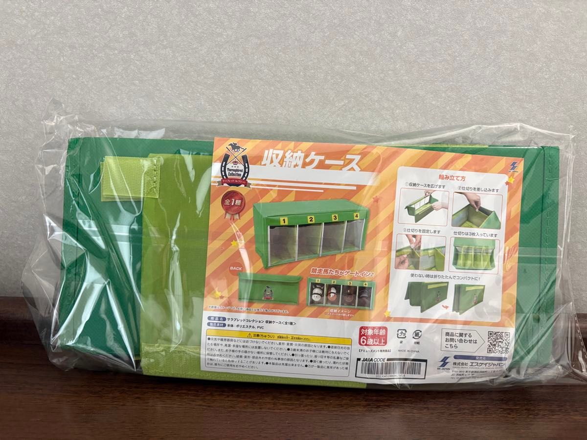 Green fabric storage case for plush toys shown in its plastic packaging with a product label and assembly diagrams visible.