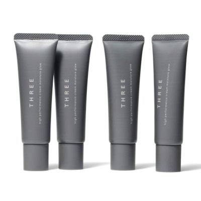 Four grey squeeze tubes of the THREE cream product shown standing against a white background.