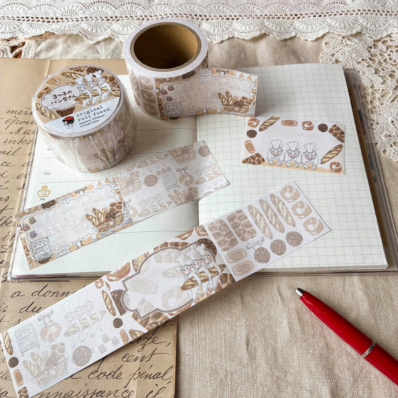 Roll sticky note tape with bakery-themed illustrations and several cut strips arranged on an open notebook.