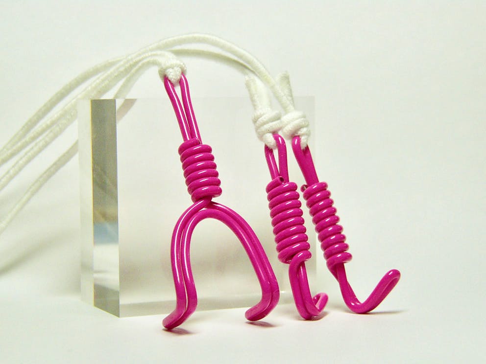 Three pink nose hooks with white cords displayed on a white background.