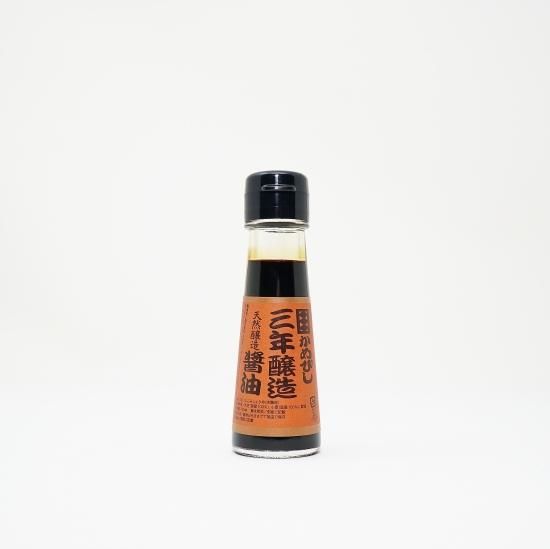A bottle of soy sauce with an orange Japanese label on a white background.
