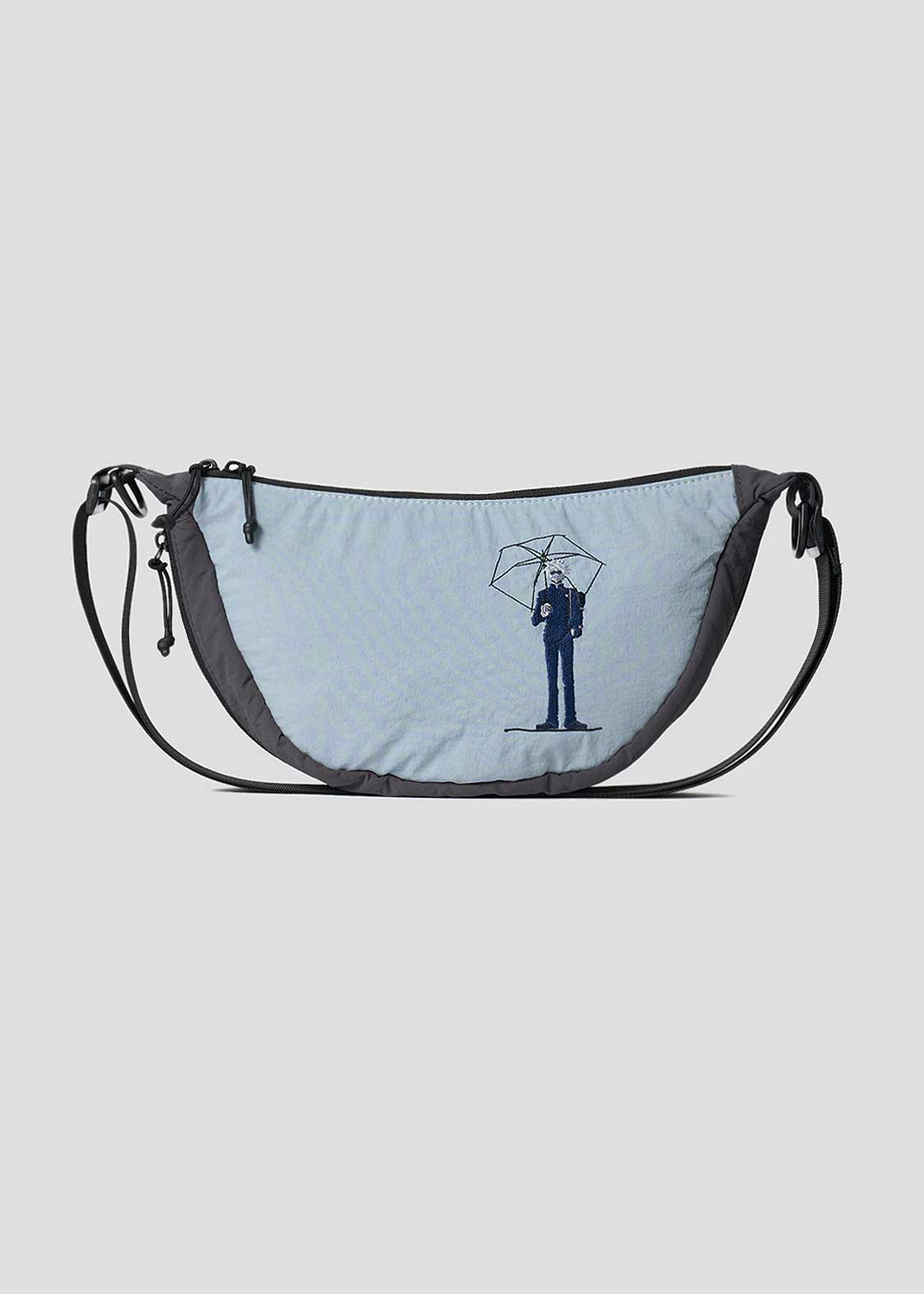 Light blue and gray mini shoulder bag with an adjustable strap and an illustration of a person holding an umbrella on the front.