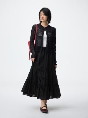 A model wearing a black tiered flare skirt shown with a cardigan and white top on a plain background.