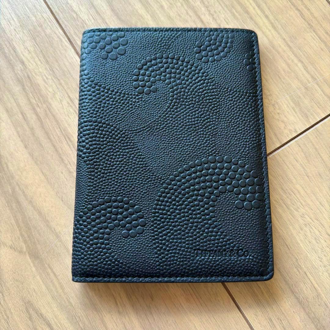 Closed black leather Tiffany & Co. passport case with a raised dot texture pattern on a wooden surface.
