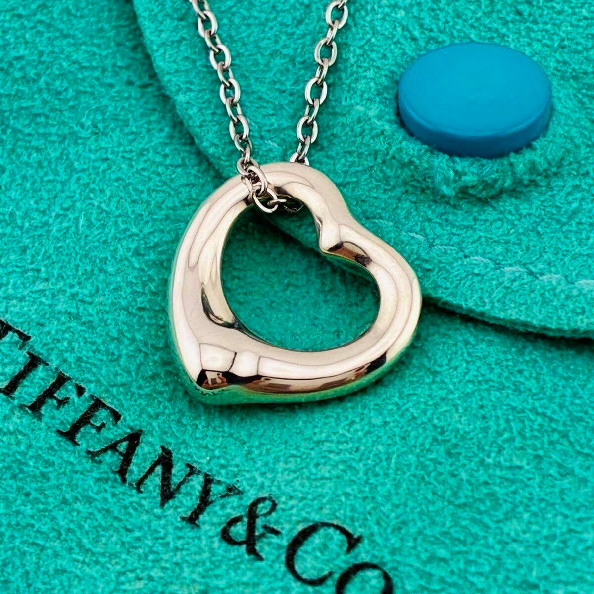Silver open-heart pendant necklace resting on a Tiffany & Co. turquoise pouch.