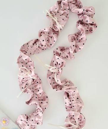 Pink polka-dot ruffled polyester shoulder phone strap with small ribbon accents laid flat on a white background.