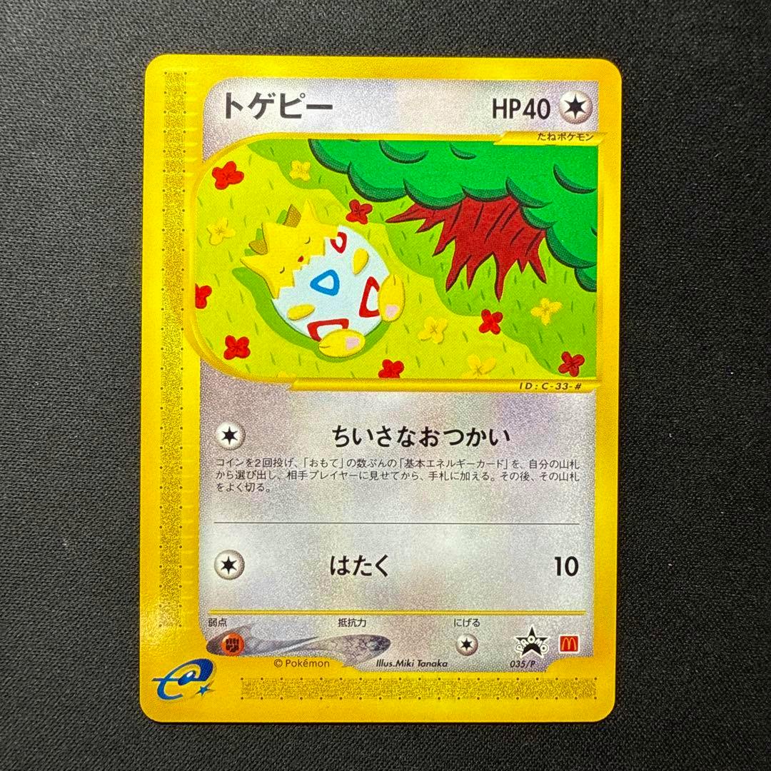 Photo of the トゲピー trading card (カードe マクドナルド 035/P) showing the full card artwork and Japanese text on a dark textured background.