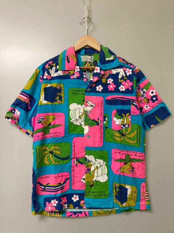 Front view of the TOHKI HAWAII rayon men's Aloha shirt with colorful floral and figurative print hanging on a wooden hanger.