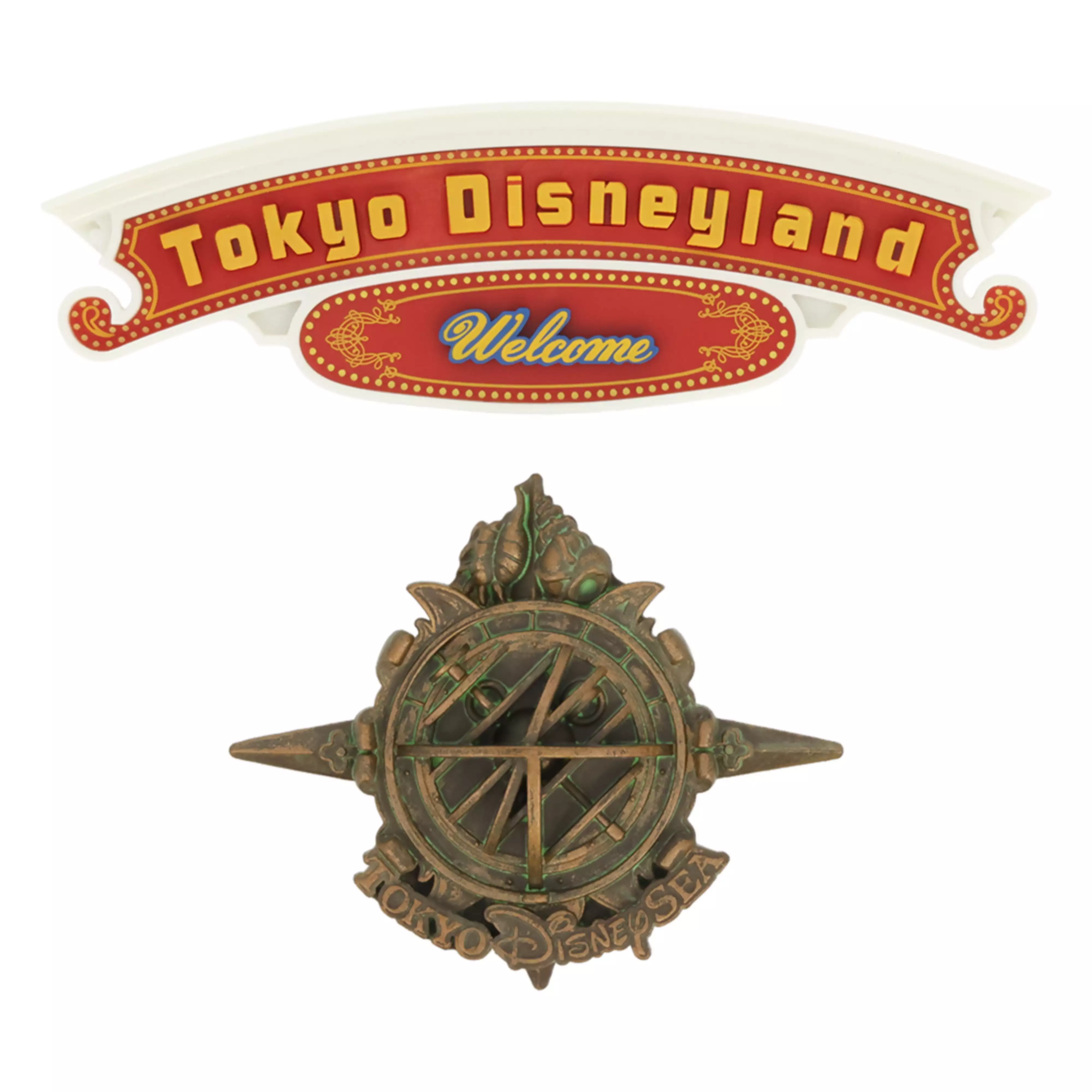 Two decorative magnets: a red "Tokyo Disneyland Welcome" banner and a bronze compass-style emblem bearing "Tokyo Disney" text.