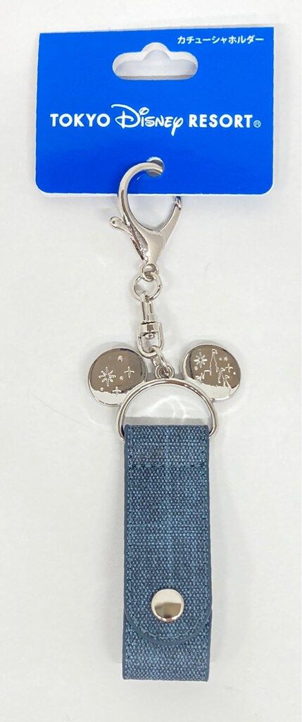 A denim headband holder bag charm with metal clasp and Mickey-ear shaped metal accents displayed on a blue Tokyo Disney Resort card.