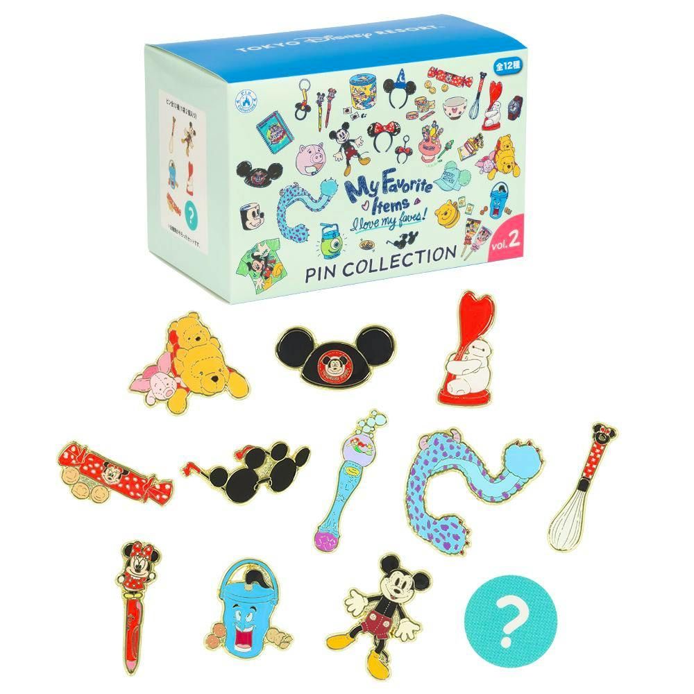 A Tokyo Disney Resort pin collection box displayed above an assortment of Disney-themed enamel pin badges arranged below.