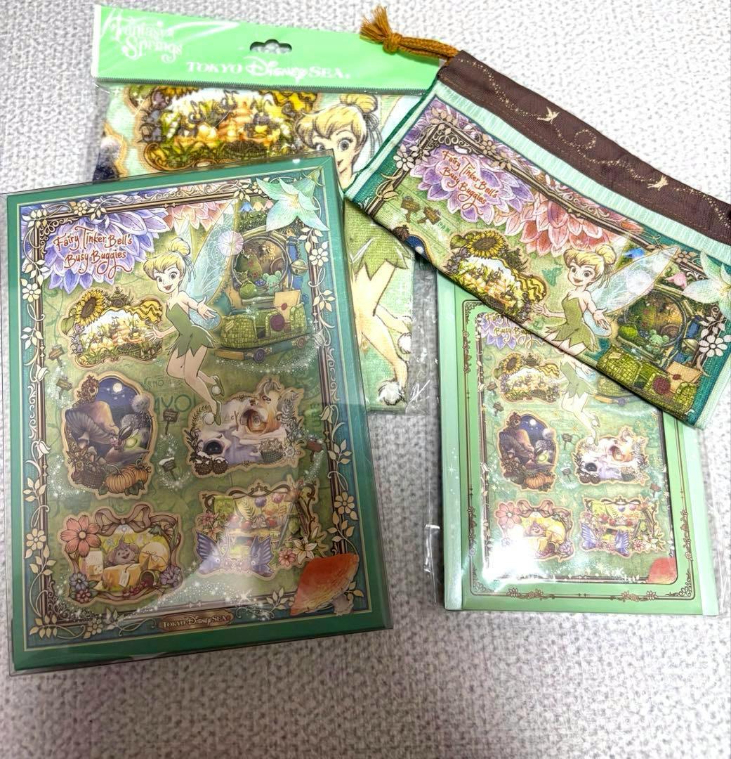 Tinker Bell–themed stationery set laid out, showing a decorative green folder, a matching notebook, and a pencil pouch with Tokyo DisneySea branding.