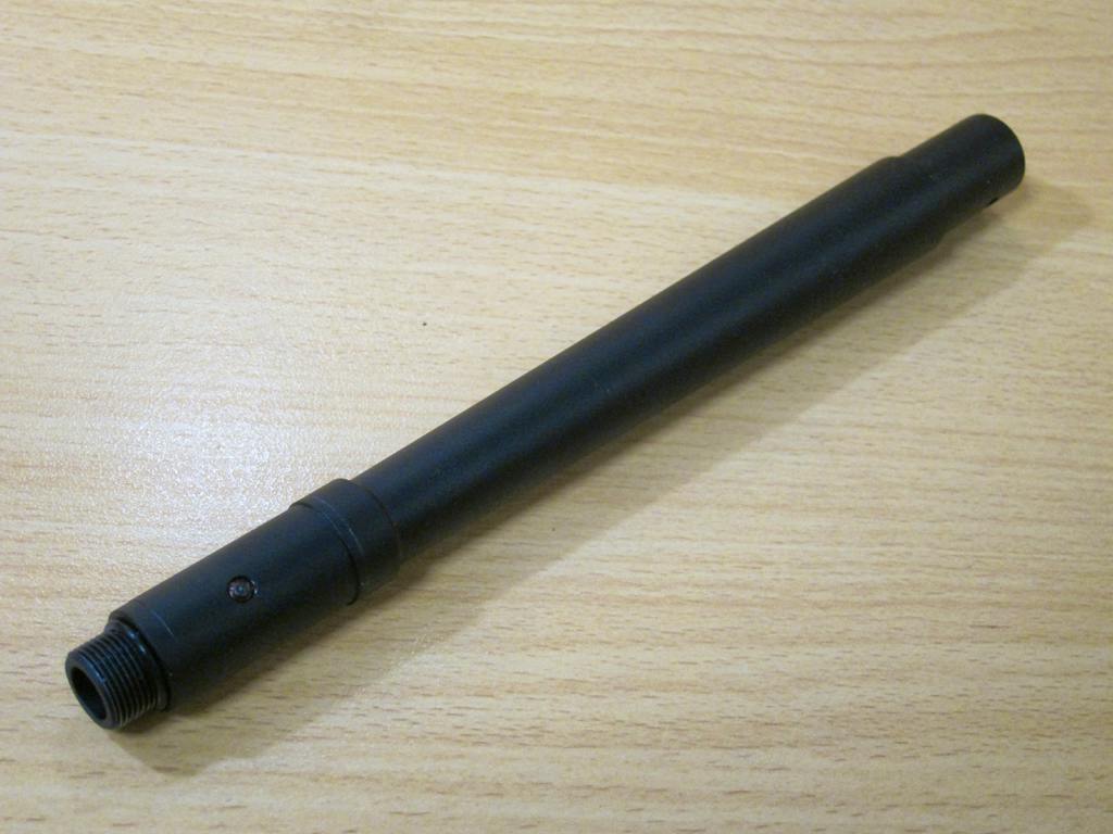 Outer barrel part for a Tokyo Marui SCAR-H airsoft gun placed on a wooden surface.