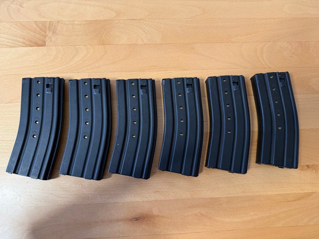 Six black magazines for a Tokyo Marui 89-style electric airsoft gun arranged on a wooden surface.