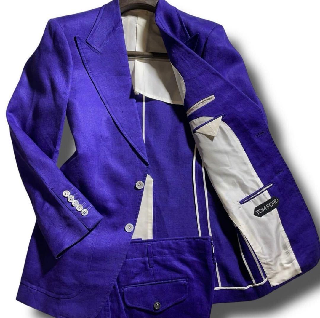 Blue-purple Tom Ford men's jacket with matching trousers shown open on a hanger, revealing white interior lining and a Tom Ford label.