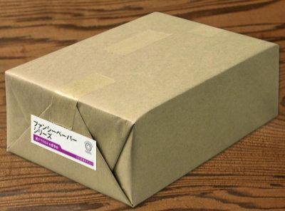 A wrapped package of writing paper in brown kraft paper with a small white label.