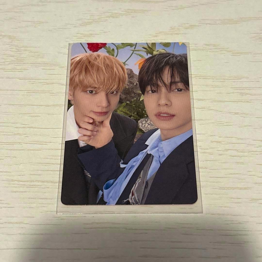 Photocard for the listed product showing two people posing, placed in a protective sleeve on a light wood surface.