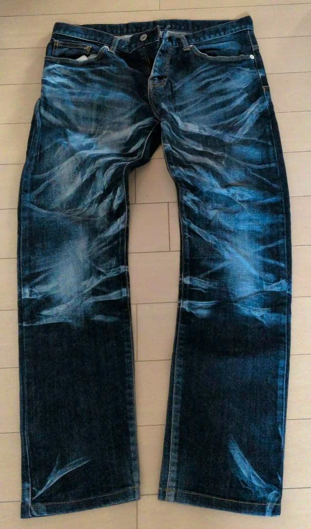 Front view of TORNADO MART denim pants laid flat on a floor.