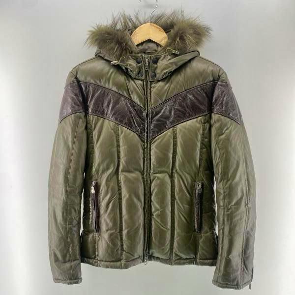 Khaki men's down jacket with leather chevron panels and a fur-trimmed hood hanging on a wooden hanger.