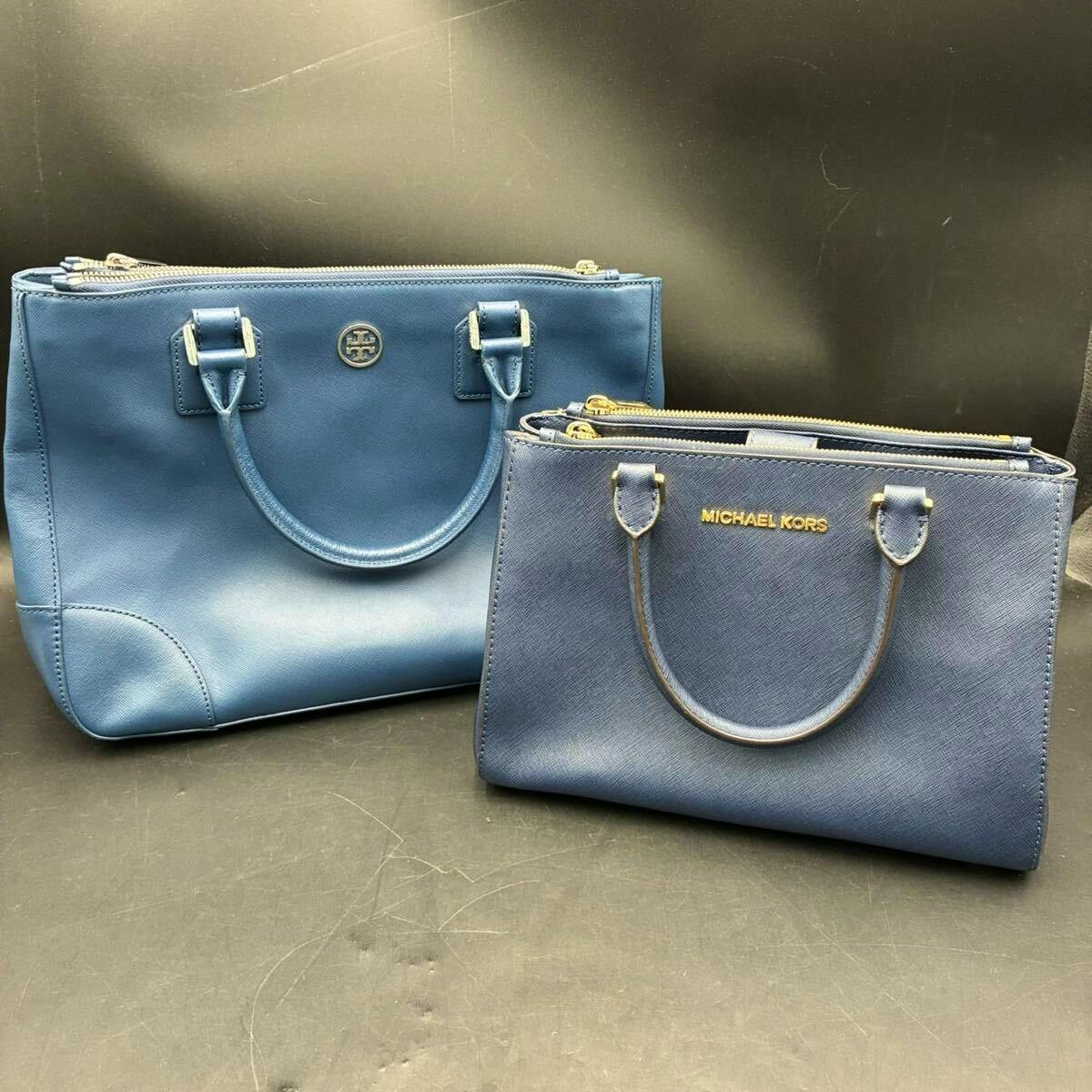 Two blue handbags (Tory Burch and Michael Kors) shown side by side on a dark background.