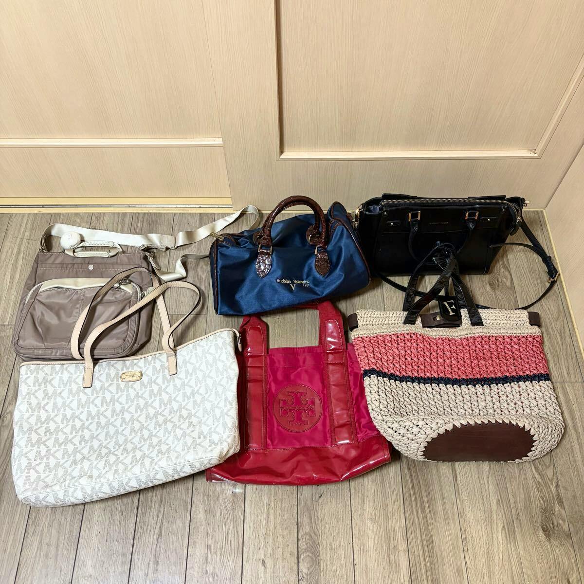 Six branded bags from a bulk set arranged on a wooden floor in front of a door.