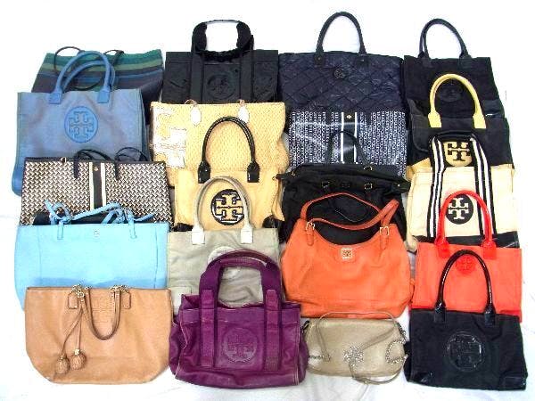 A grid of Tory Burch tote and shoulder bags in assorted colors and styles laid flat on a surface.