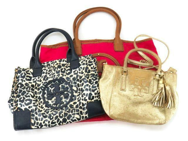 Three women's Tory Burch bags—a red tote, a leopard-print handbag with black trim, and a small metallic gold leather bag—arranged on a white background.
