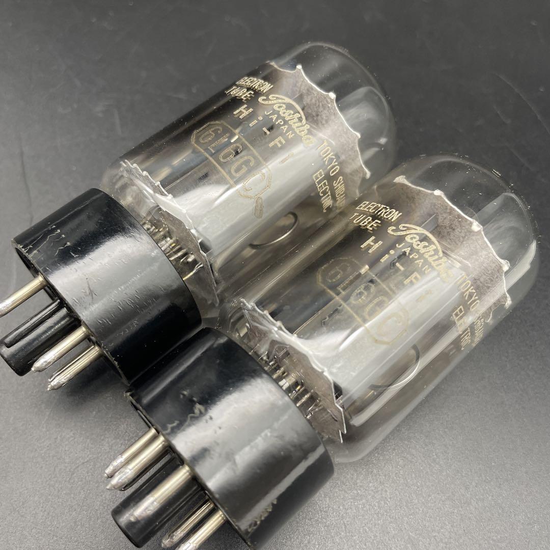 Pair of Toshiba 6L6GC vacuum tubes with black bases photographed on a dark surface.