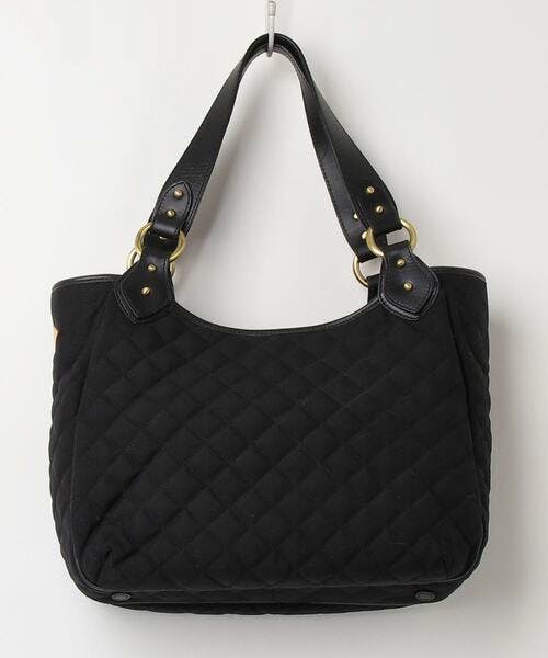 Black quilted tote bag with leather straps hanging on a hook.