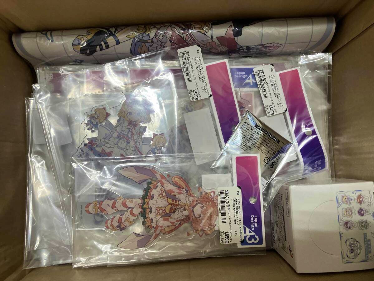 Overhead view of a cardboard box filled with multiple individually sealed acrylic decorative stands and small boxed accessories.