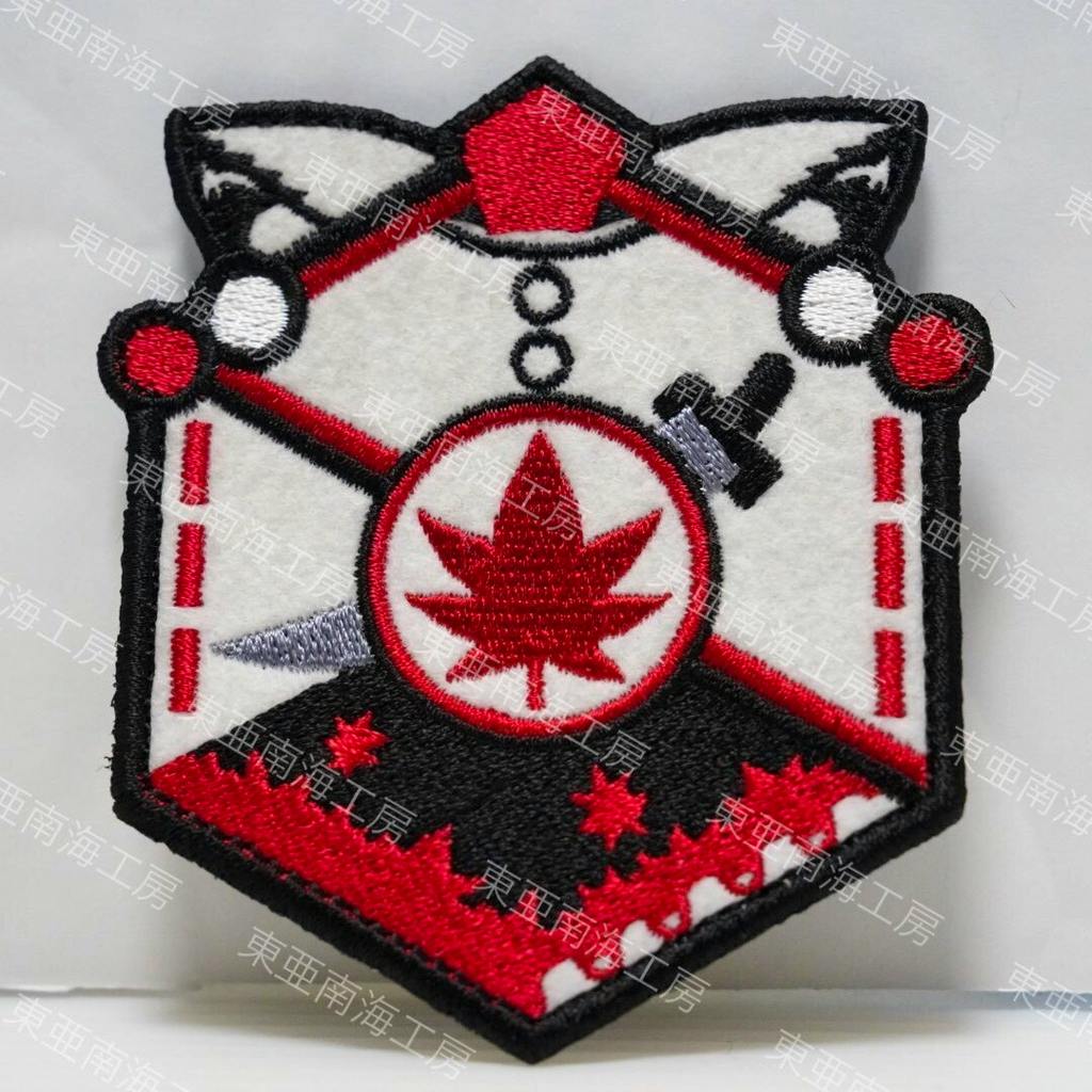 Close-up photo of the embroidered Touhou Project velcro patch for 犬走椛 (Inubashiri Momiji) featuring a red maple-leaf emblem.