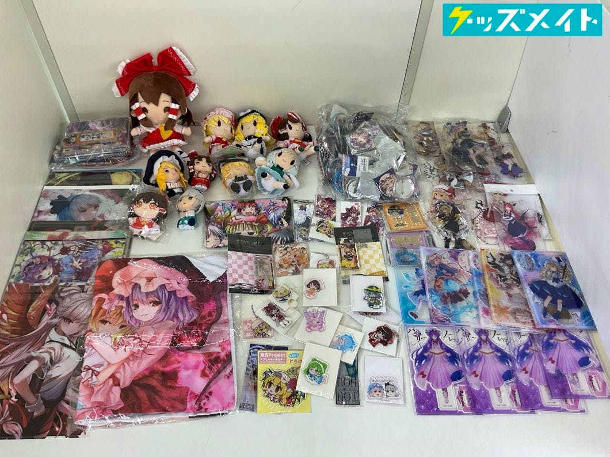 Photo of a spread of Touhou Project merchandise including plush mascots, acrylic stands, badges, and other goods.