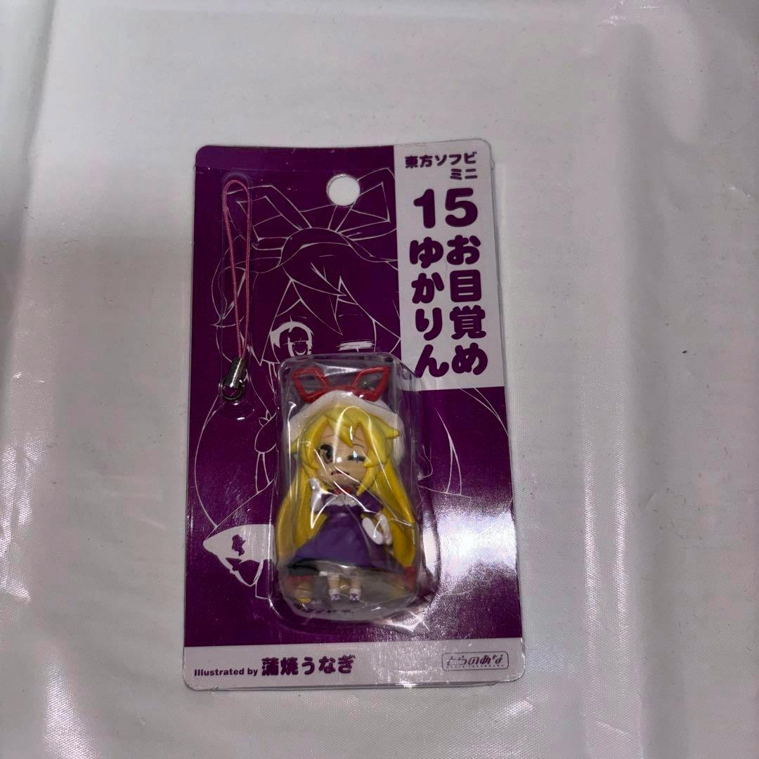 Front view of the packaged soft vinyl mini figure strap shown in its blister card, with the small figure and strap visible.