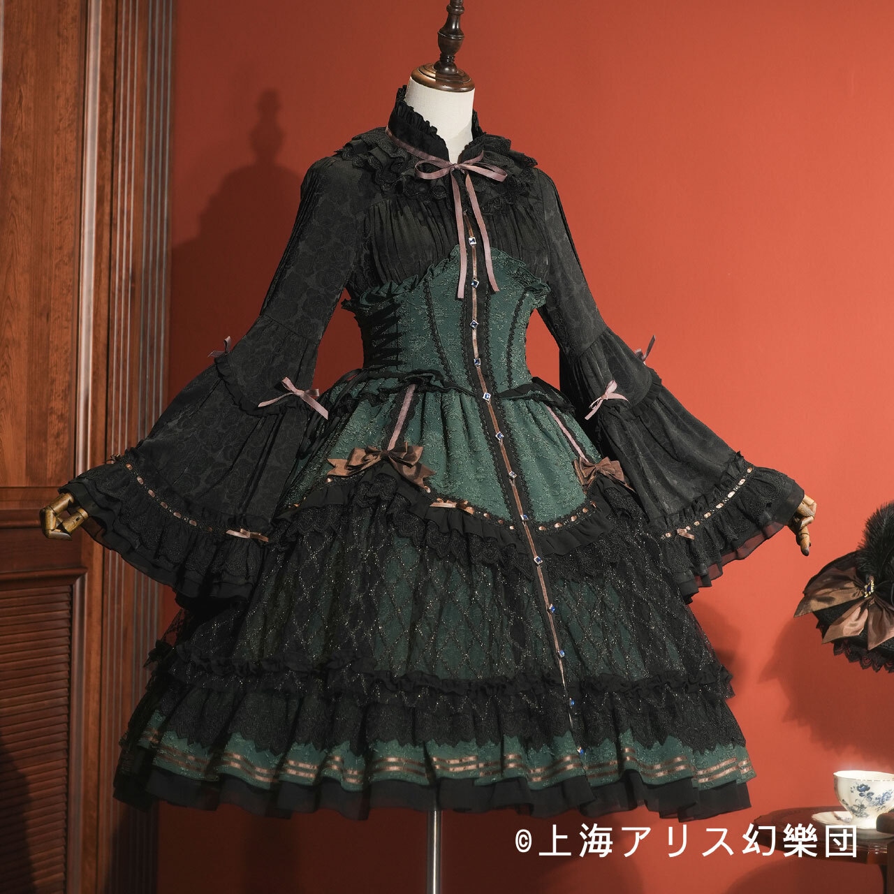 Corset-style green and black women's dress displayed on a mannequin against a red wall.
