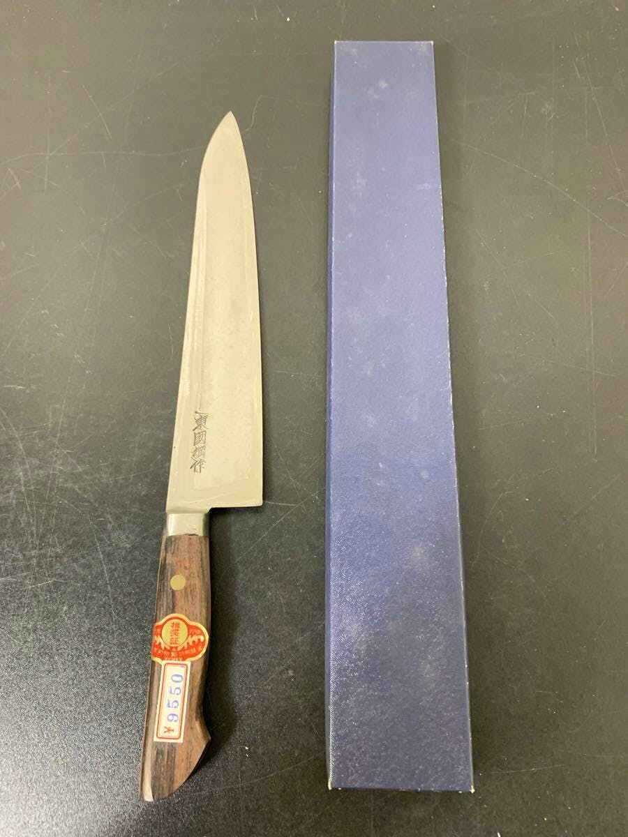 Chef knife (24cm) with a wooden handle shown next to its blue box on a dark surface.