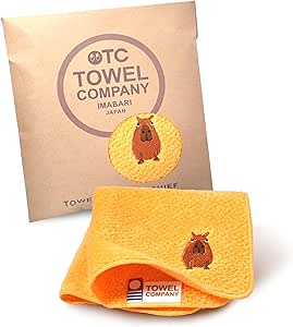 Apricot Imabari cotton handkerchief with a small capybara embroidery displayed with its Towel Company packaging.