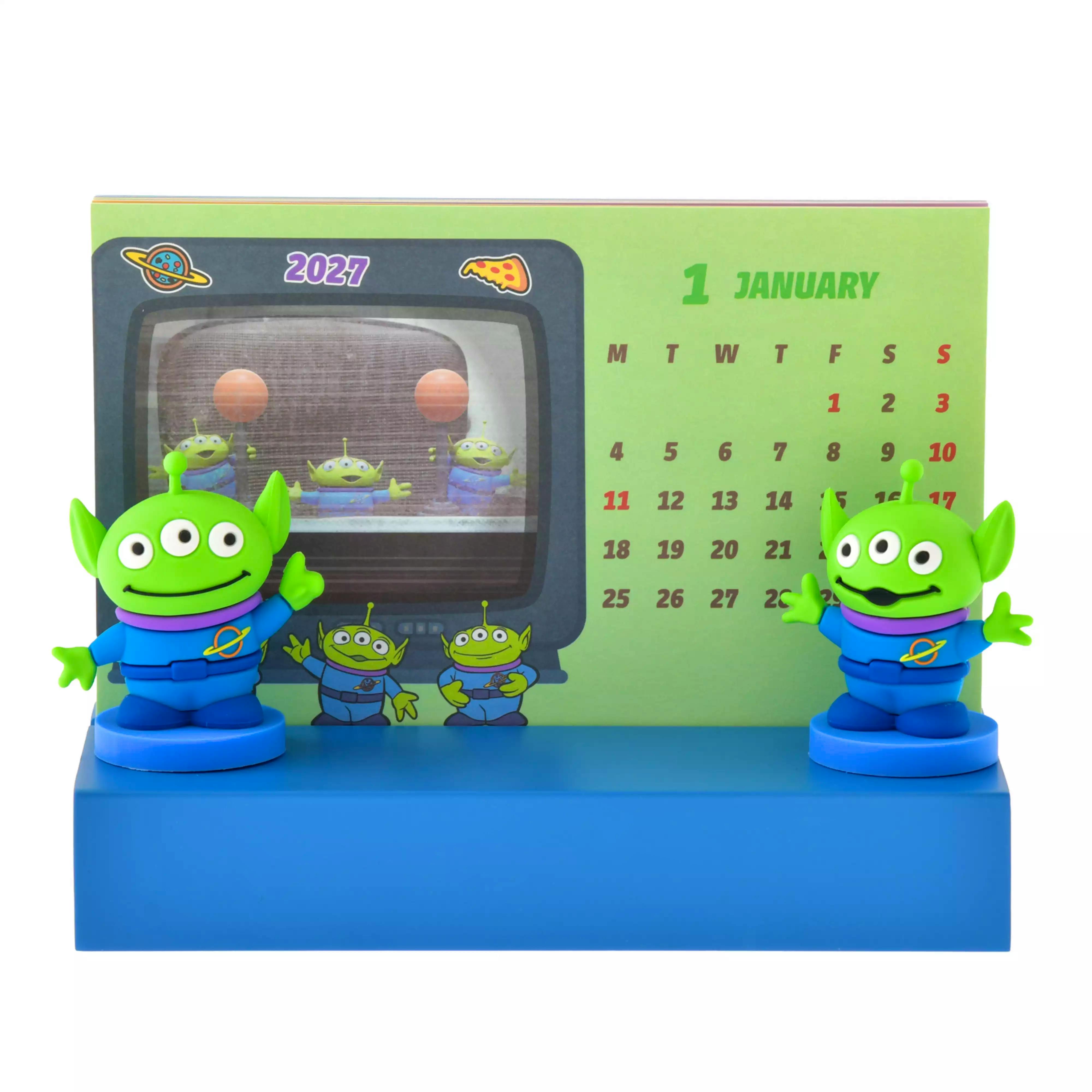 Toy Story 2027 desk calendar on a blue base with two green alien figurines and a visible monthly calendar grid.