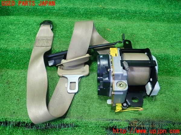 Driver's seat belt assembly (beige) with buckle and retractor displayed on a green mat.