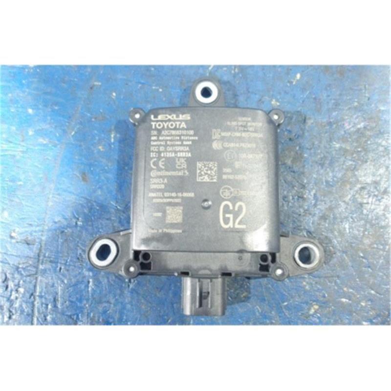 Front view of a Toyota/Lexus car radar sensor unit with mounting tabs and an electrical connector placed on a blue surface.