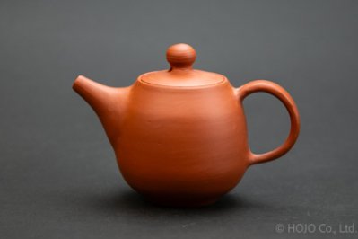 A brown porcelain teapot on a gray background.