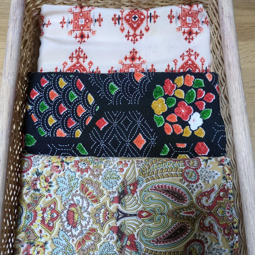 Three folded fabric pieces with traditional patterns arranged in a woven basket.