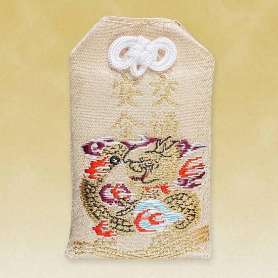 A beige cloth traffic safety amulet embroidered with a dragon and gold 交通安全 characters.